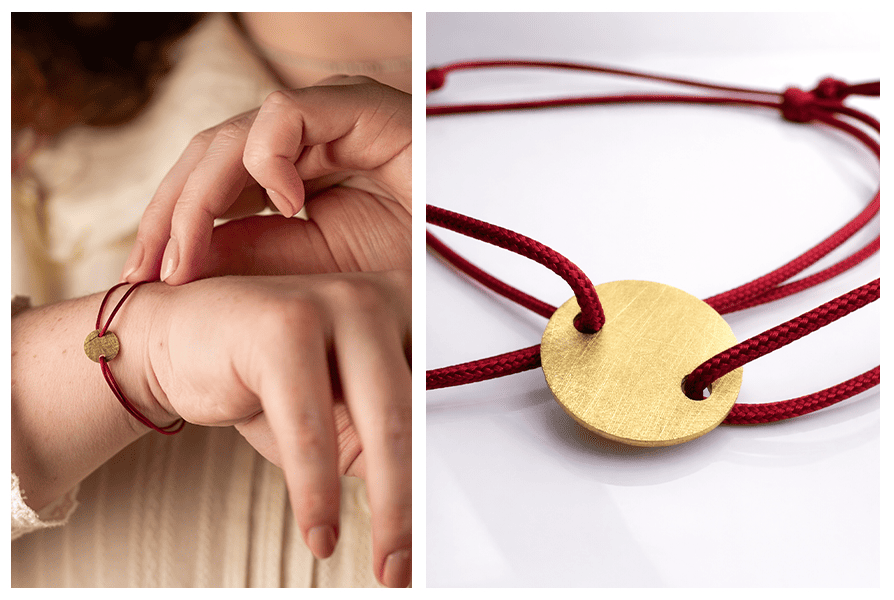 Zbliżenie na szczotkowaną zawieszkę w kolorze złota na czerwonym sznurku – detal wykończenia bransoletki