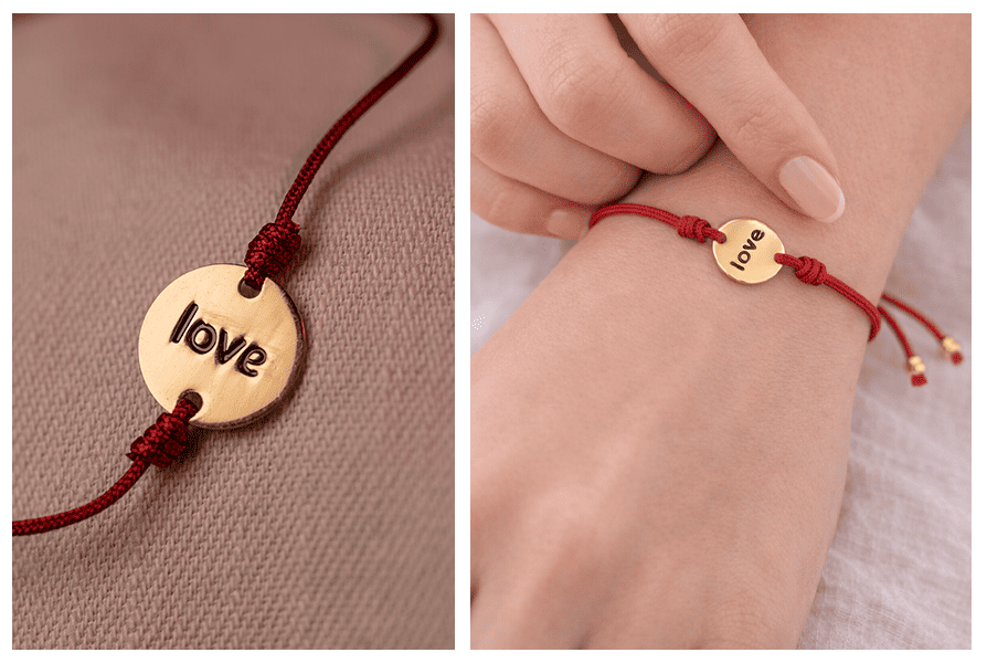 Zbliżenie na złoty medalik z napisem „love” na czerwonym sznurku; obok bransoletka na nadgarstku, palce chwytają zawieszkę i widać regulację