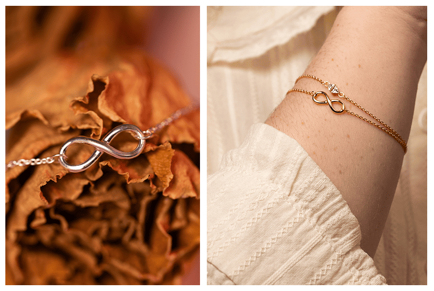 Zbliżenie na srebrny symbol nieskończoności na tle suszonych liści; po prawej złota bransoletka ze znakiem nieskończoności na ręce, z delikatnym łańcuszkiem