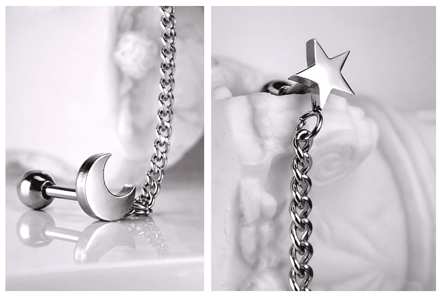 Srebrny kolczyk do dwóch dziurek z motywem księżyca i gwiazdki połączonych łańcuszkiem, pokazany w dużym zbliżeniu z widocznymi detalami zawieszek
