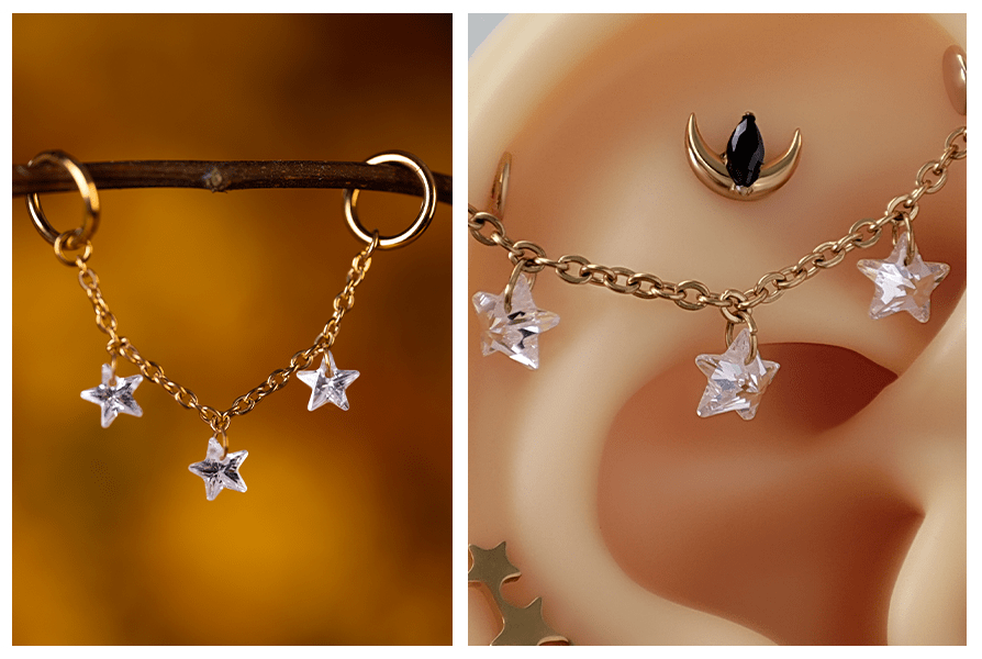 Złoty łańcuszek z trzema wiszącymi gwiazdkami z kryształu, zawieszony między dwoma kolczykami kółkami i pokazany na silikonowym modelu ucha z dodatkowymi kolczykami