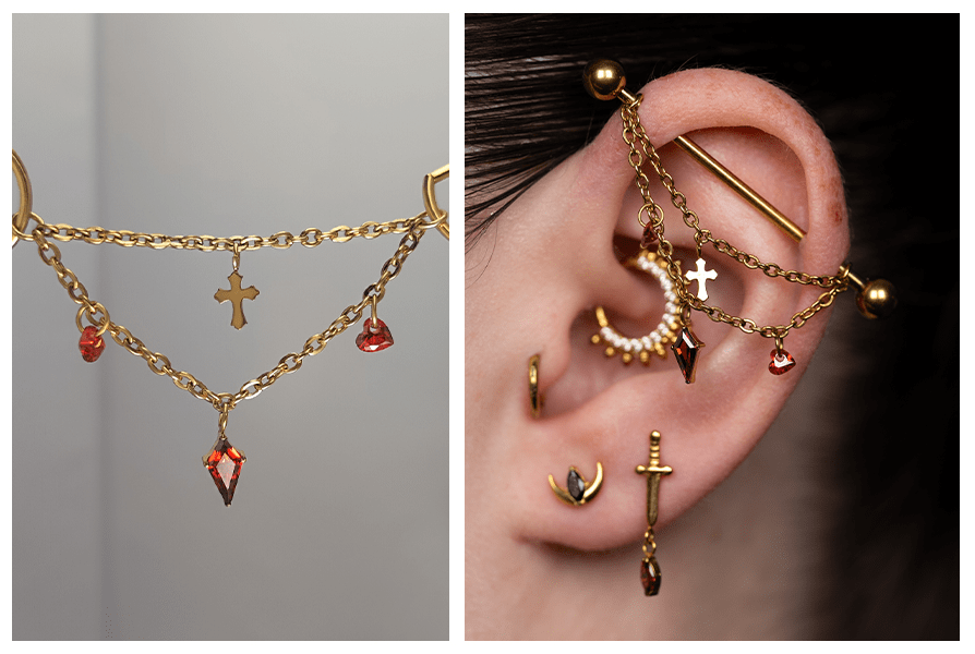 Złoty łańcuszek krzyż z dwoma czerwonymi sercami do kolczyków, pokazany zbliżeniowo i założony na uchu z innymi kolczykami