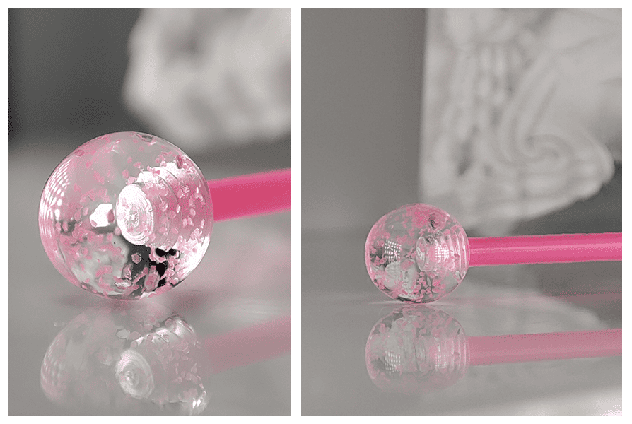 Różowy kolczyk do języka z brokatowymi kulkami w zbliżeniu, pokazujący połysk, transparentny efekt kulek i detal ozdobnego wykończenia
