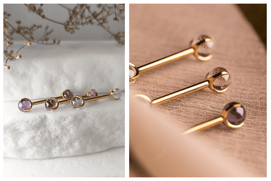 Złota sztanga z przezroczystymi kulkami – kilka sztuk ułożonych na jasnym tle i na tkaninie, widoczne kolory kulek