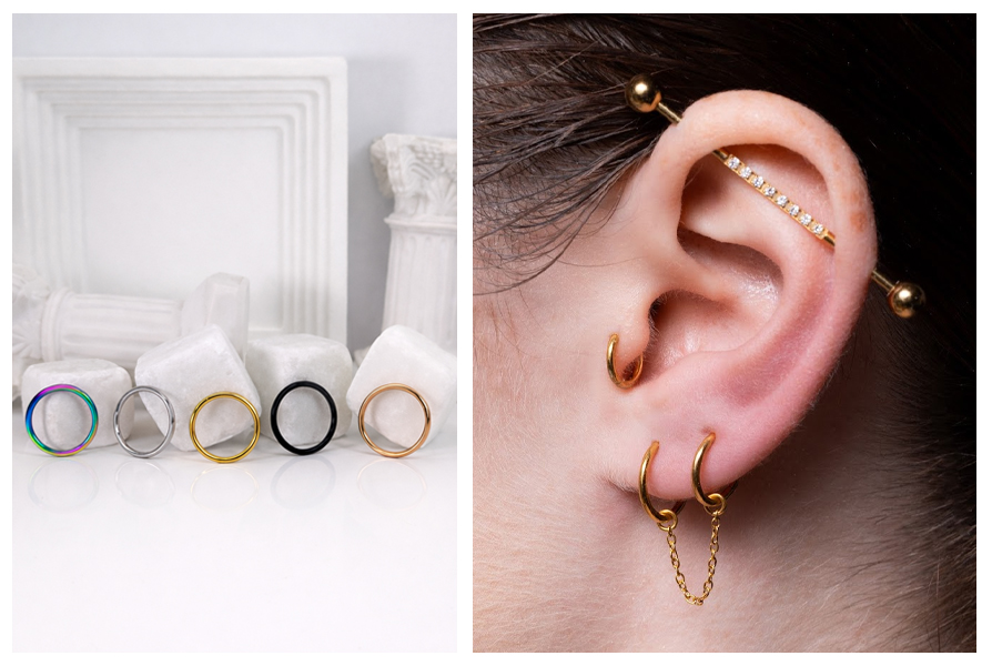 Pięć stalowych kółek clicker w różnych kolorach stoi na białym tle, a obok widać ucho w złotej stylizacji z kilkoma kolczykami