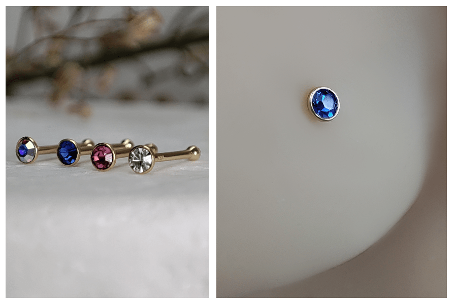 Rząd prostych kolczyków do nosa z okrągłym kryształkiem w różnych kolorach na jasnym, marmurowym tle oraz zbliżenie niebieskiego kryształka w złotej oprawie w skrzydełku nosa