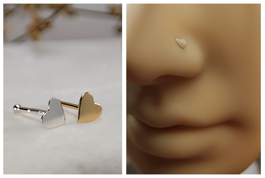 Dwa proste kolczyki do nosa z serduszkiem w kolorze srebrnym i złotym na jasnym kamieniu oraz zbliżenie złotego serduszka w skrzydełku nosa