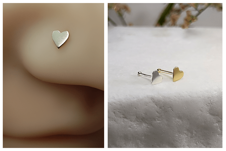 Srebrny prosty kolczyk do nosa z małym serduszkiem założony w nosie manekina oraz komplet złotego i srebrnego kolczyka z sercem na marmurowym tle