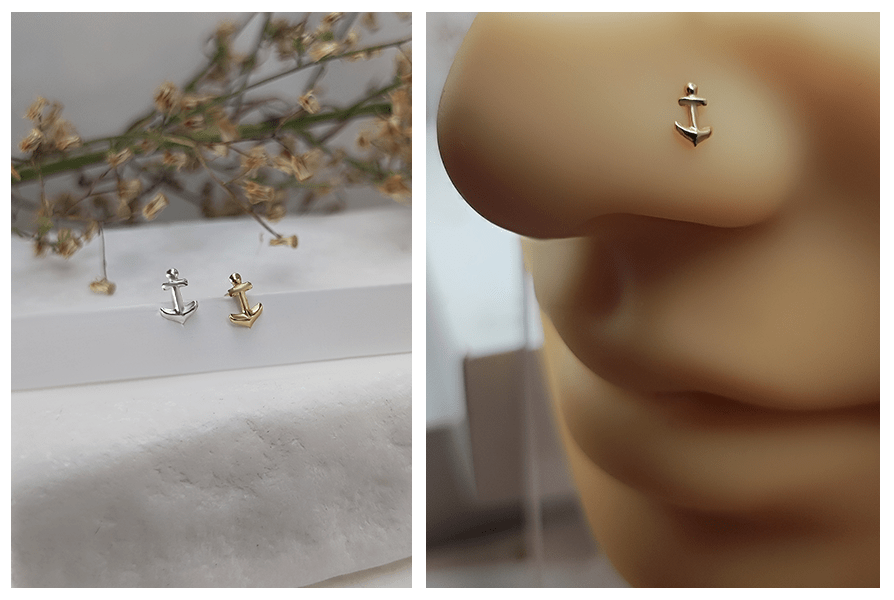 Dwa zakręcone kolczyki do nosa z kotwiczką w kolorze srebrnym i złotym na jasnym kamieniu oraz zbliżenie złotej kotwicy w skrzydełku nosa
