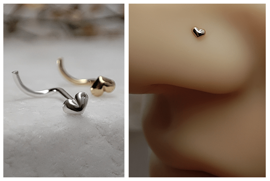 Dwa zakręcone kolczyki do nosa z wypukłym serduszkiem w kolorze srebrnym i złotym na marmurowej podstawie oraz zbliżenie złotego serca w piercingu nosa