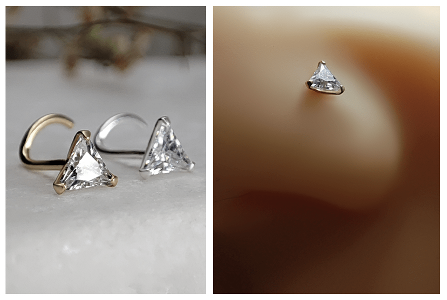 Zakręcony kolczyk do nosa z trójkątnym przezroczystym kryształem w złotej i srebrnej oprawie na marmurowym tle oraz zbliżenie kolczyka w nosie