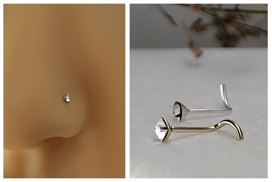 Delikatny zakręcony kolczyk do nosa z małym kwadratowym kryształem założony w nosie  oraz ujęcie złotej i srebrnej wersji kolczyka leżących na białym kamieniu