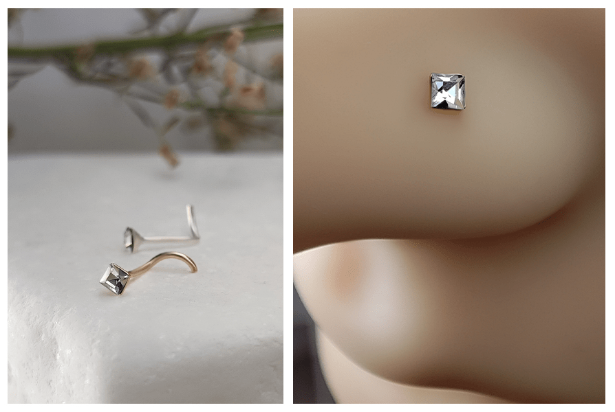 Zakręcony kolczyk do nosa z jasnym kwadratowym kryształkiem pokazany z profilu w nosie oraz para kolczyków z kwadratowym kryształem na jasnym, marmurowym tle