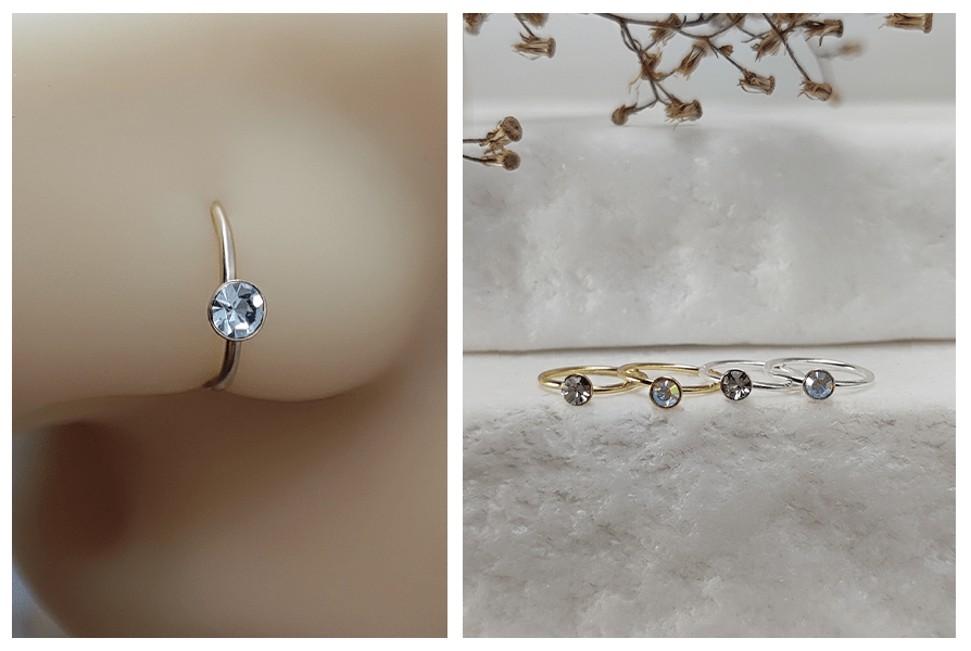 Delikatne rozginany kolczyk typu kółko z drobnym kryształkiem, zbliżenie na nosie oraz trzy kolczyki na jasnym kamiennym tle