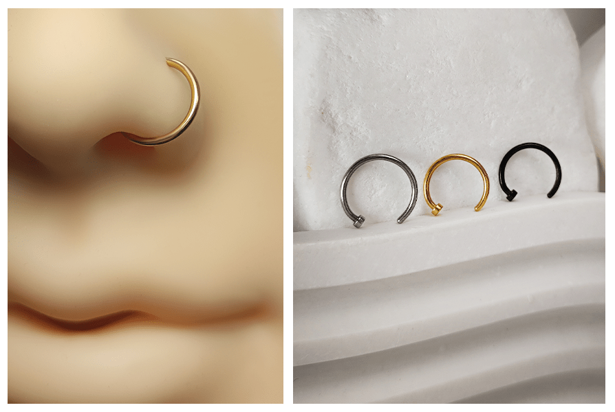 Złoty kolczyk do nosa otwarte kółko zaprezentowany na silikonowym modelu nosa oraz trzy kółka w kolorze srebrnym, złotym i czarnym ustawione na białym kamiennym tle