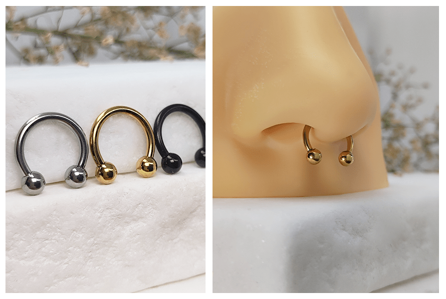 Stalowe podkówki z kulkami w trzech kolorach: srebrnym, złotym i czarnym na białym kamiennym tle oraz złota podkówka z kulkami założona w piercingu nosa septum na silikonowym modelu
