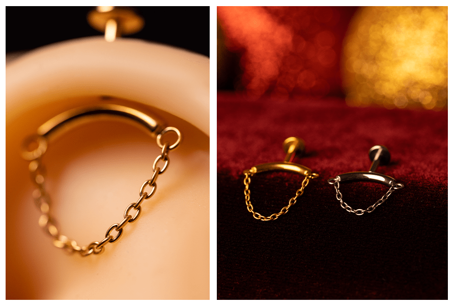 Zbliżenie na labret do vertical helix z prostym łańcuszkiem (detal ogniwek) oraz porównanie wersji złotej i srebrnej leżących na czerwonym, welurowym tle