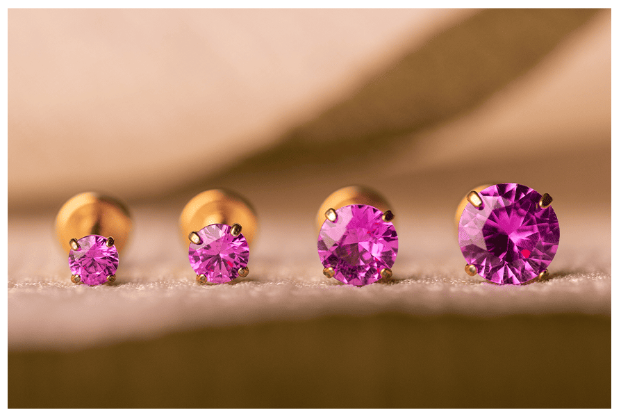 Labret z kryształkiem w pazurkach – różowy kamień w czterech rozmiarach, ujęcie makro na jasnym tle