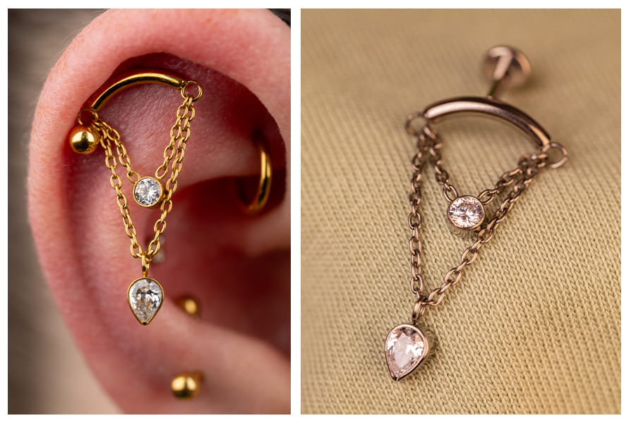 Zbliżenie na złoty labret z dwoma łańcuszkami, okrągłą cyrkonią i zawieszką w kształcie łezki, noszony w górnej części ucha