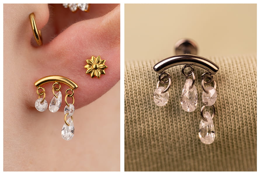 Zbliżenie na złoty labret z delikatnie wiszącymi cyrkoniami, noszony w płatku ucha obok małego kolczyka w kształcie kwiatka