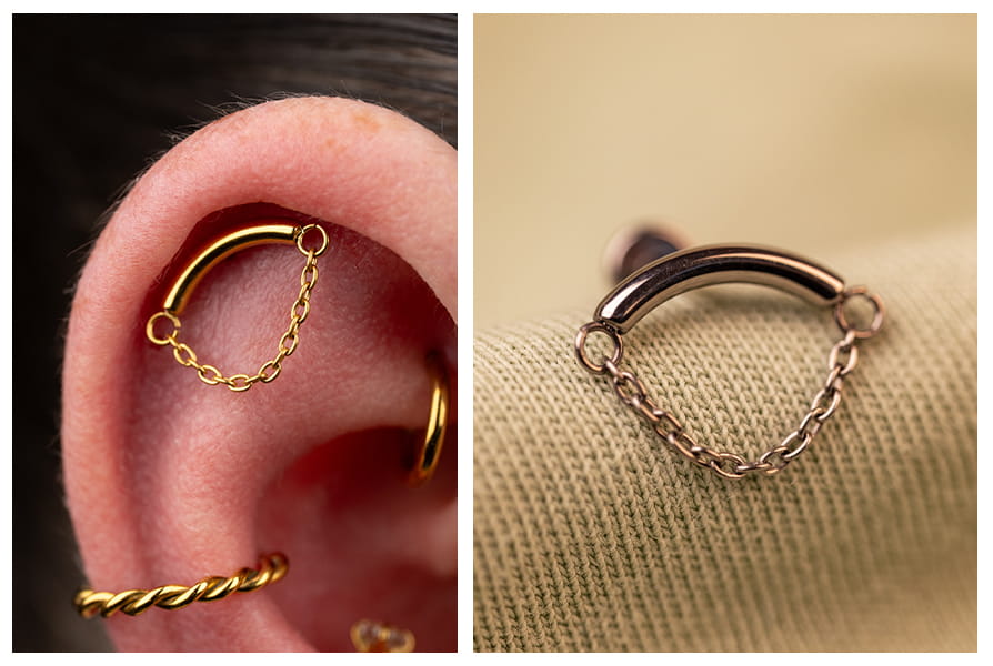 Złoty labret z delikatnym łańcuszkiem subtelnie układającym się pod łukiem kolczyka, pokazany w zbliżeniu na uchu