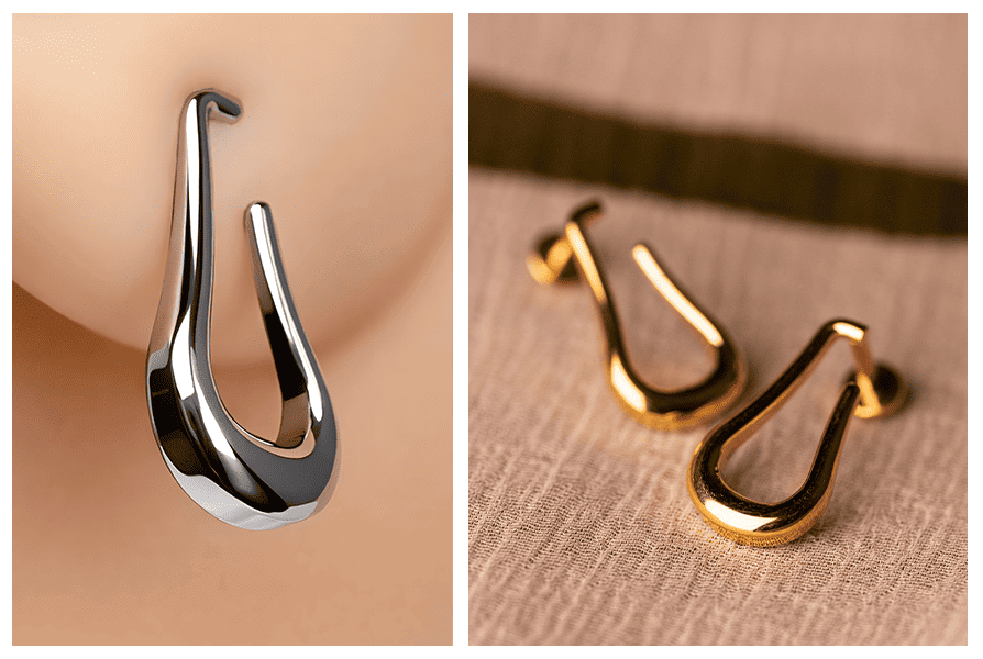 Detal srebrnej otwartej łezki na uchu oraz dwa złote labrety z otwartą łezką pokazane na materiale w zbliżeniu